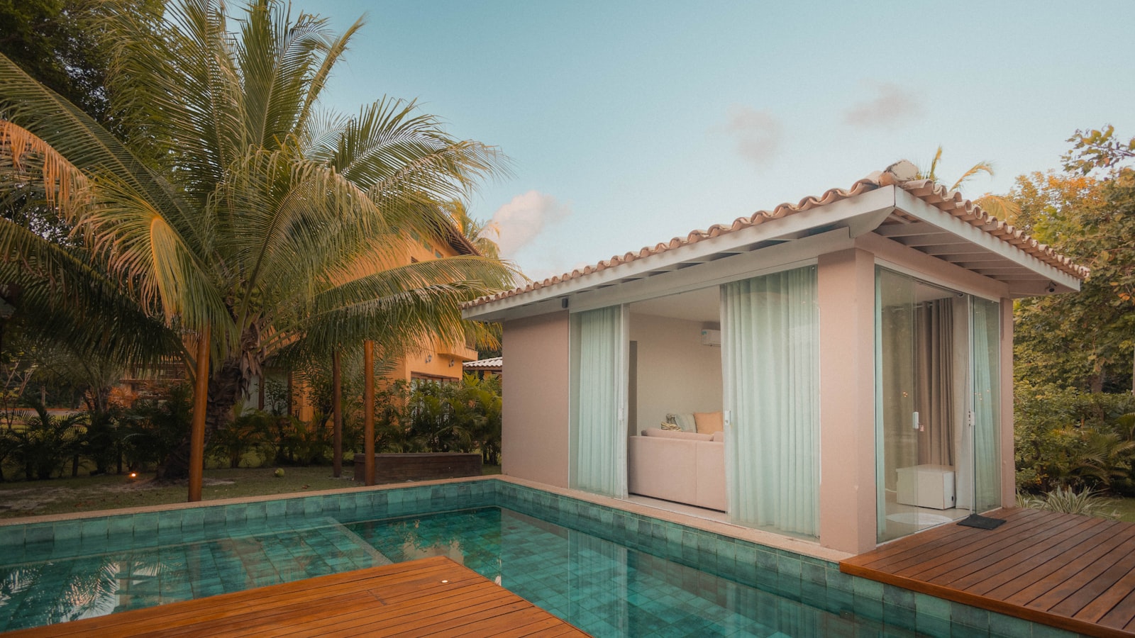 Tropical poolside cabana with palm trees and pool.